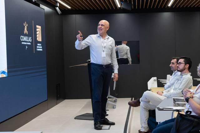 Un presentador está hablando frente a un público en una sala moderna.