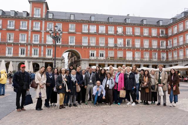Un grupo de personas posando en una plaza con un edificio histórico de fondo.