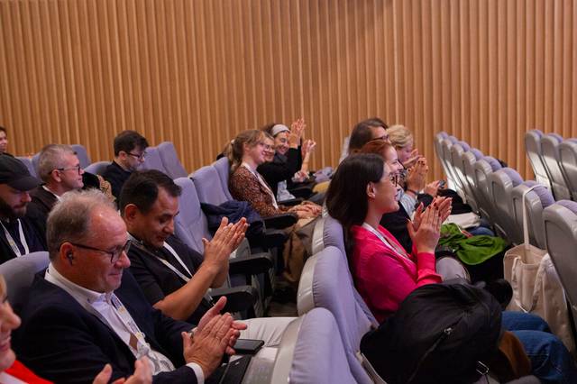 Un grupo de personas aplaudiendo en un auditorio durante un evento.