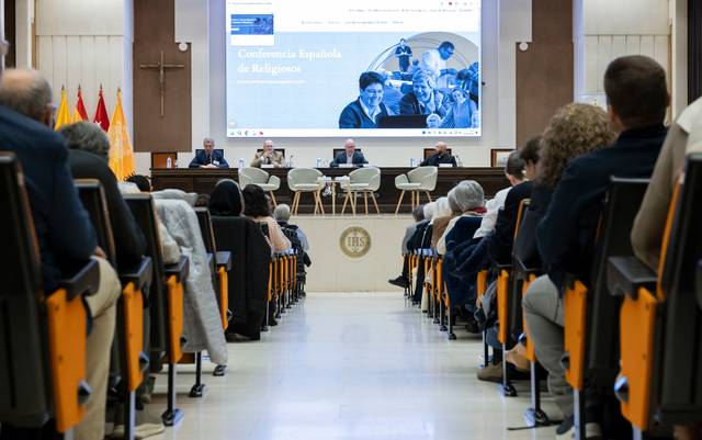 Una conferencia con varias personas sentadas en un panel y una audiencia frente a ellos.