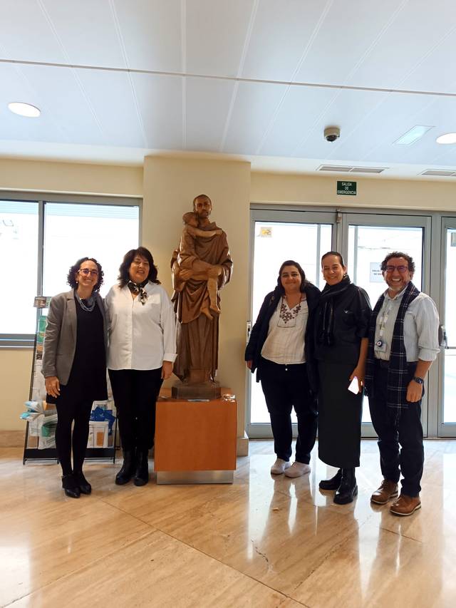 Cinco personas posan sonrientes junto a una estatua en un vestíbulo iluminado.