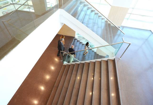 Un grupo de personas conversando junto a una escalera moderna en un espacio bien iluminado.