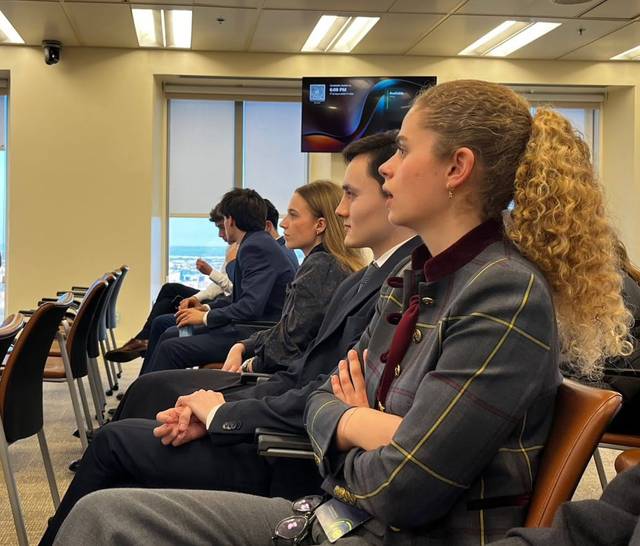 Un grupo de jóvenes sentados en una sala, prestando atención durante una presentación.