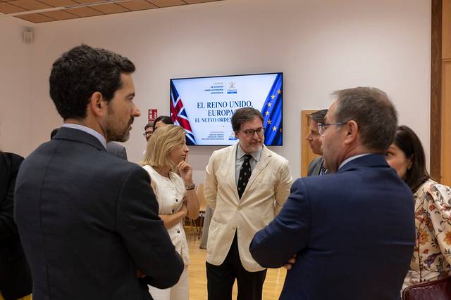 Un grupo de personas discute en una sala mientras una pantalla muestra un cartel sobre el Reino Unido y Europa.