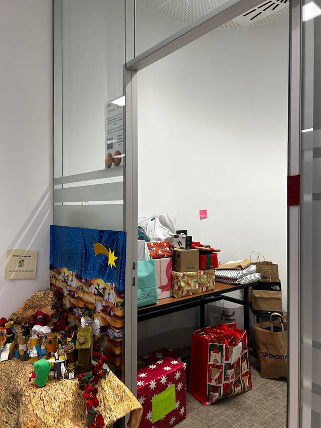 Una pequeña sala decorada con regalos y adornos festivos.