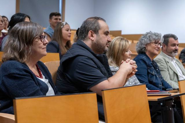 Un grupo de personas sentadas en un auditorio durante un evento.