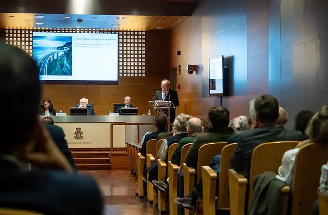 Un evento formal con un orador en el podio ante un público atento.