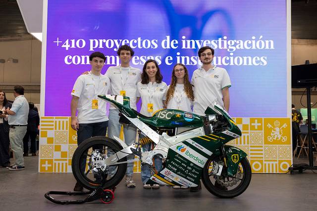 Un grupo de estudiantes presenta una moto en un evento relacionado con proyectos de investigación.