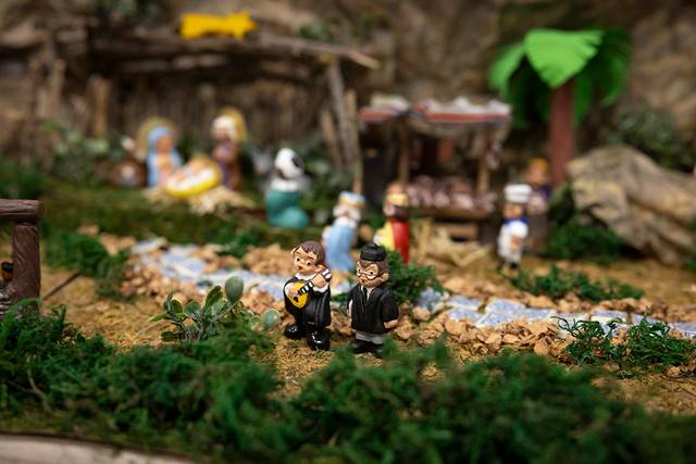 La imagen muestra una escena de un belén artesanal con figuras en miniatura en un entorno natural.