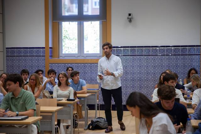 Un profesor interactúa con sus alumnos en un aula mientras ellos prestan atención.