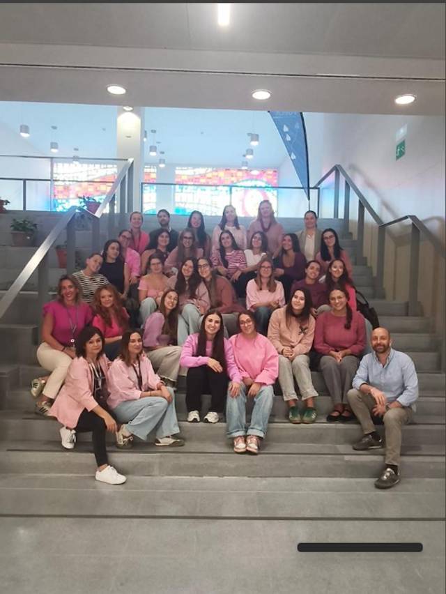 Un grupo de mujeres vestidas de rosa se sienta en las escaleras de un edificio.