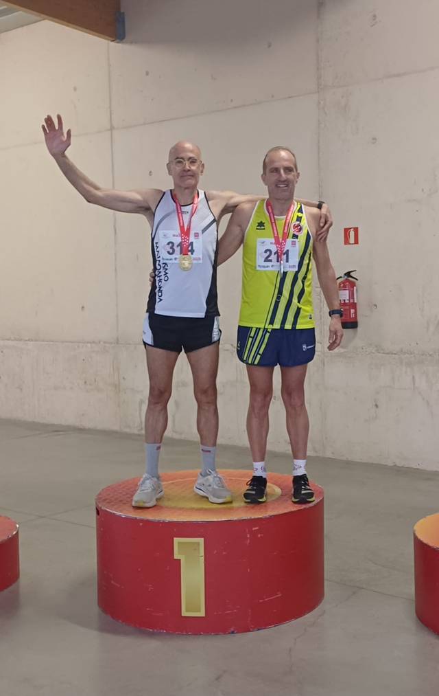 Dos corredores de pie en un podio, celebrando sus medallas tras una competición.