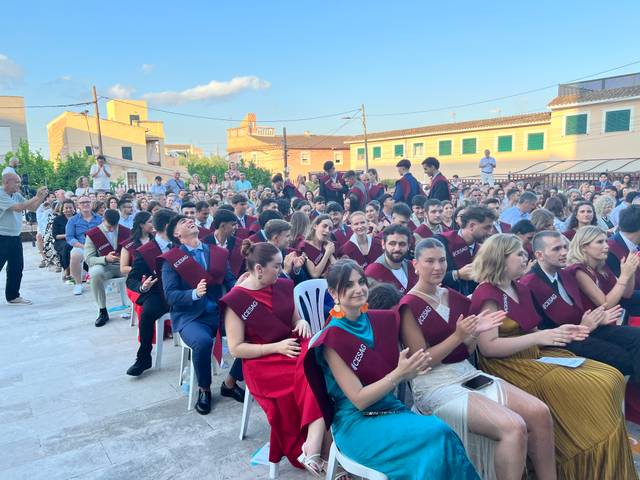Una ceremonia de graduación al aire libre con un gran número de asistentes.