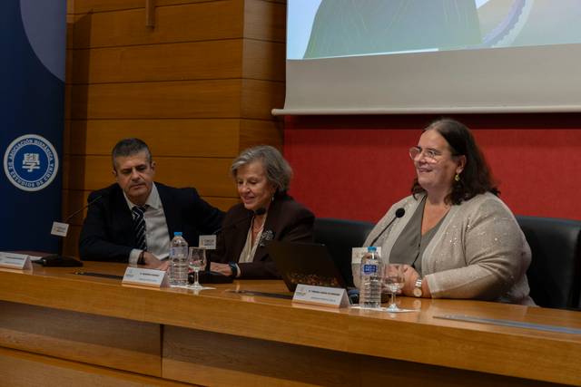 Tres personas participan en una mesa de debate durante un evento en un auditorio.