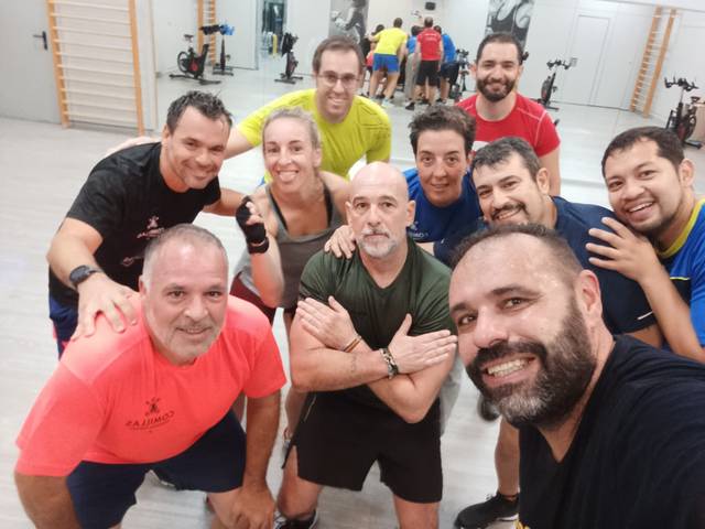 Un grupo de personas sonrientes posan juntas en un ambiente de entrenamiento deportivo.