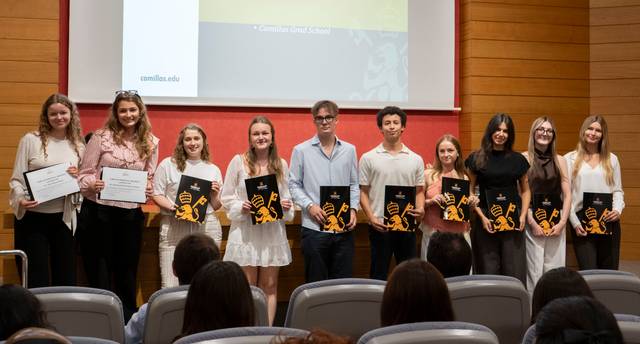 Un grupo de estudiantes sonríe mientras sostienen sus diplomas en un evento de premiación.
