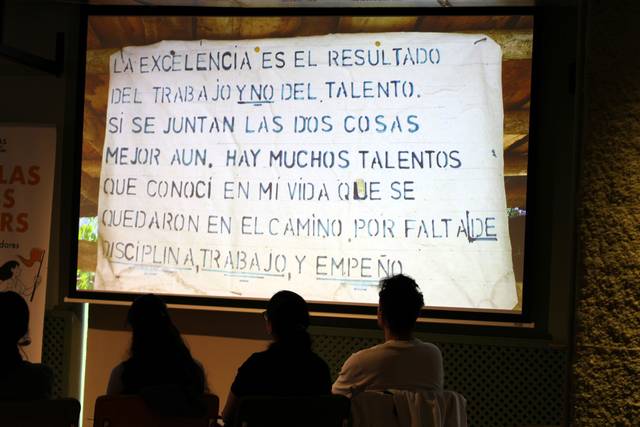 Una proyección en la que se observa un mensaje sobre la importancia del trabajo y la disciplina para alcanzar la excelencia.