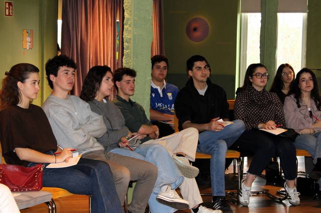 Un grupo de jóvenes escucha atentamente durante una presentación en un salón.