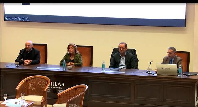 Cuatro personas sentadas en una mesa durante una conferencia en una sala con decoración clásica.