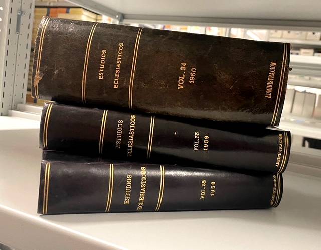 Tres volúmenes de la revista 'Estudios Eclesiásticos' apilados en una estantería.