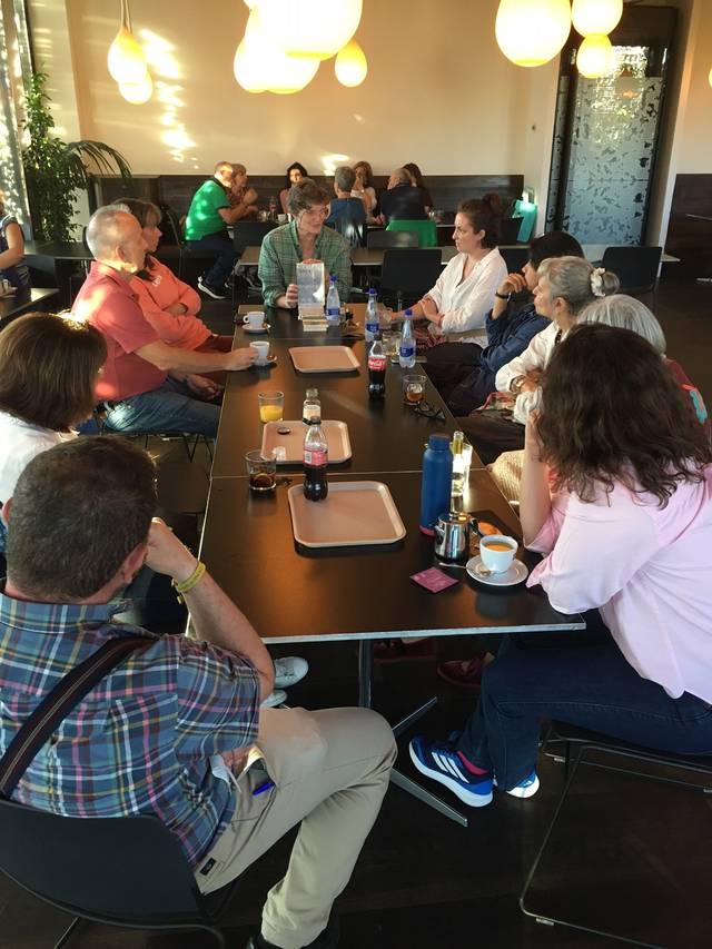 Un grupo de personas sentadas en una mesa de café, conversando y compartiendo un momento social.