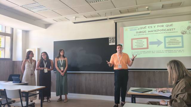 Un grupo de cuatro personas presenta un proyecto en un aula con una pantalla de presentación.