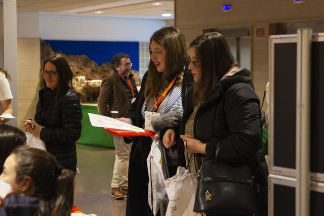 Un grupo de personas se encuentra en un evento, conversando y revisando documentos.