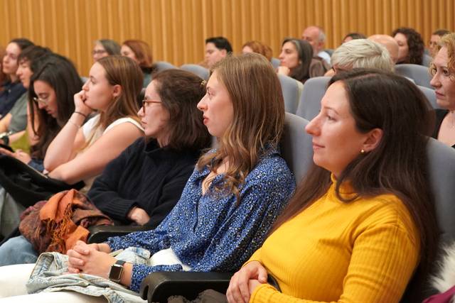 Un grupo de personas sentadas en un auditorio prestando atención a un evento.