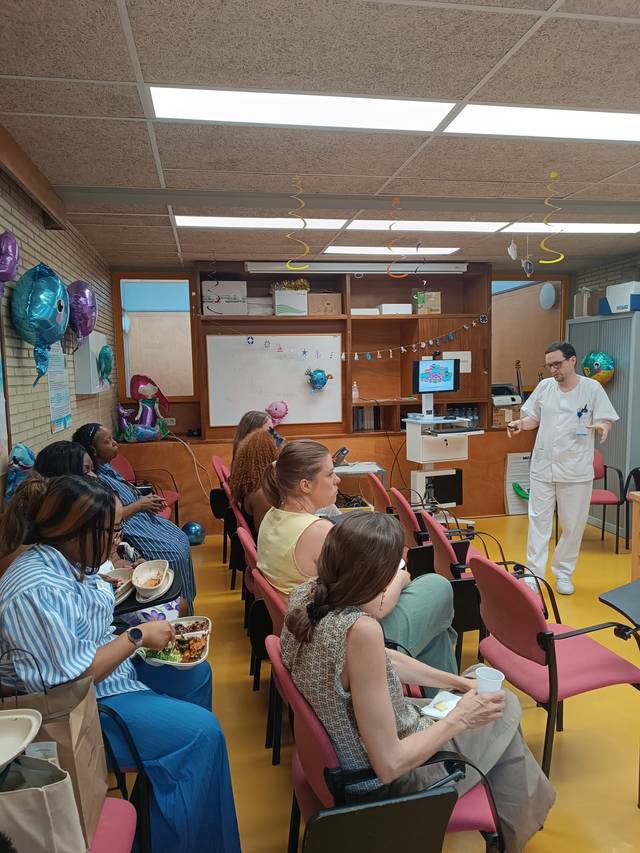 Un grupo de personas sentadas en una sala, atendiendo a un evento mientras el personal médico les presenta información.
