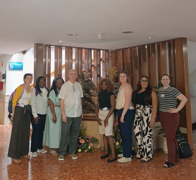 Un grupo de personas posando frente a una escultura en un ambiente interior.