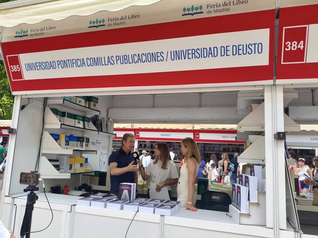 Una feria del libro con un stand de la Universidad Pontificia Comillas y la Universidad de Deusto.