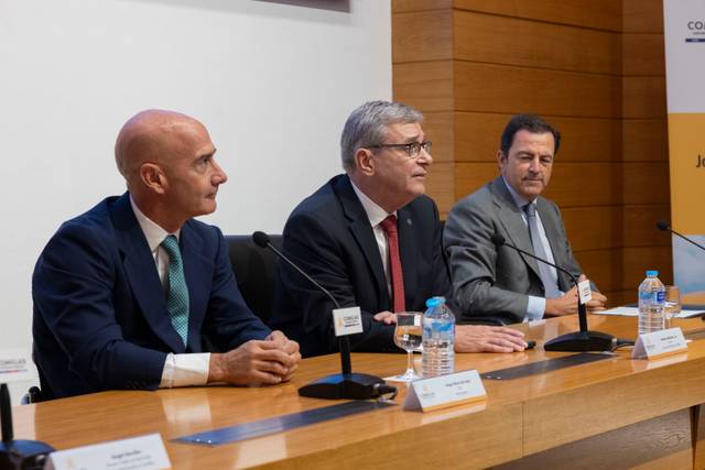 Tres hombres sentados en una mesa durante un evento o conferencia.