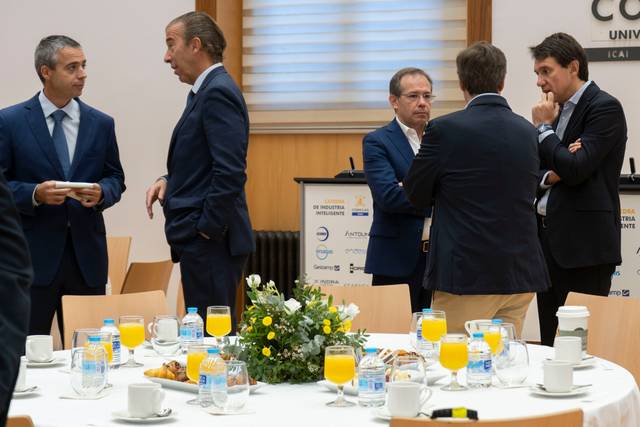 Un grupo de hombres conversando en un evento con una mesa decorada y bebidas.
