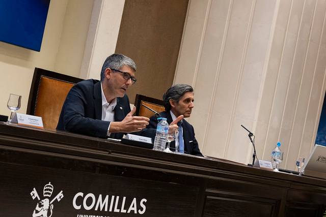 Dos hombres discutiendo en un panel de conferencias en la Universidad de Comillas.