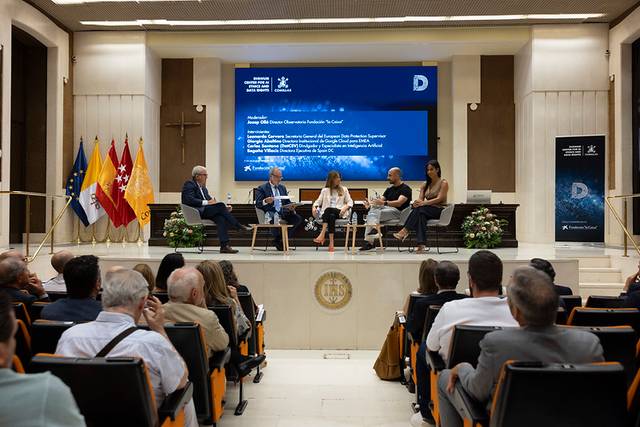 Una mesa redonda con varios ponentes discutiendo en un auditorio con público presente.