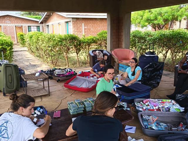 Un grupo de personas organizando maletas y artículos personales en un espacio al aire libre.
