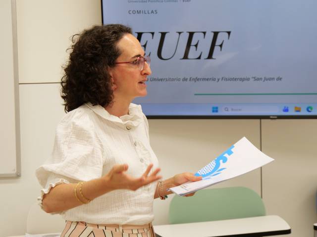 Una mujer habla en una presentación mientras sostiene unos documentos en sus manos.
