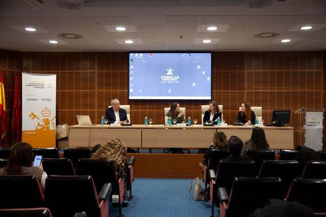 Una mesa redonda con varias personas sentadas en un panel frente a una audiencia en una sala de conferencias.