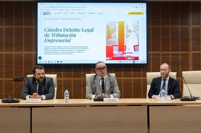 Tres personas sentadas en una mesa durante un evento relacionado con la Cátedra Deloitte Legal de Tributación Empresarial.
