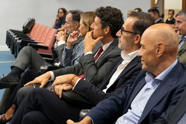 Un grupo de personas sentadas en un auditorio prestando atención a una presentación.