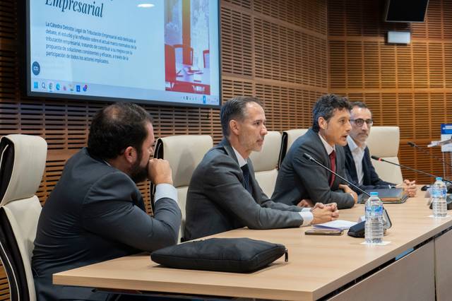 Cuatro personas sentadas en una mesa durante una presentación empresarial.