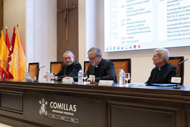 Imagen de un evento en la Universidad Pontificia Comillas con tres ponentes en una mesa.