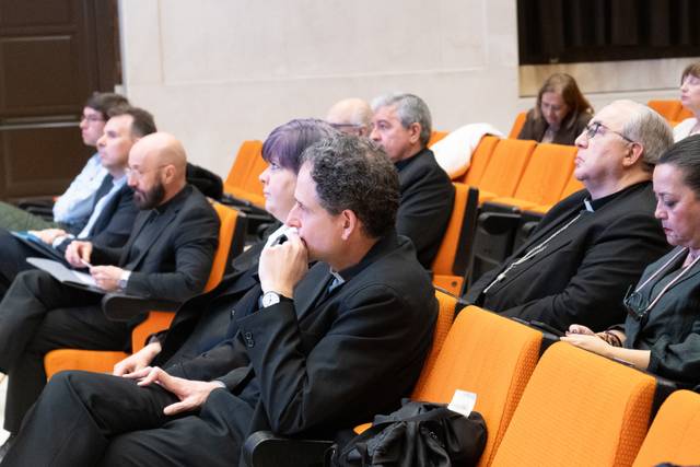 Un grupo de personas sentadas en un auditorio prestando atención a una presentación.