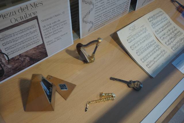 Una mesa con varios instrumentos musicales y partituras exhibidos en un museo.