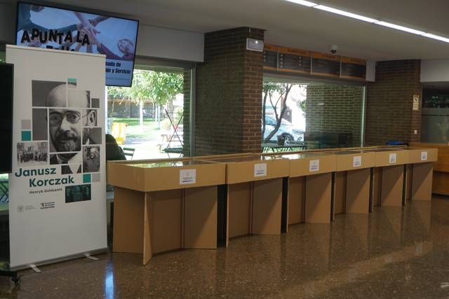 Una exposición dedicada a Janusz Korczak en un espacio público con mesas de exhibición.
