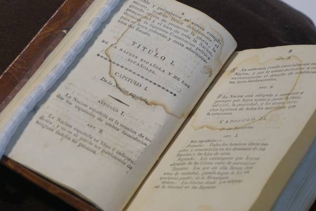 Un libro antiguo abierto que muestra páginas con texto impreso y algunos signos de deterioro.