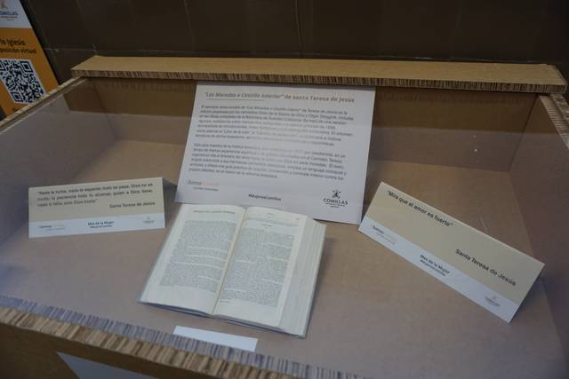 Una vitrina con un libro abierto y varias etiquetas explicativas en un entorno de exhibición.