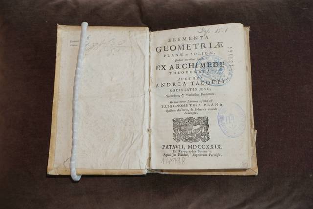 Un libro antiguo titulado 'Elementa Geometriae' de Archimedes, mostrando páginas con sellos y la firma de un propietario.