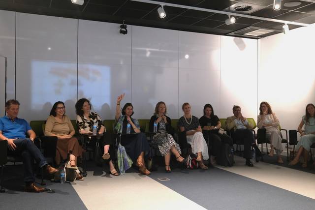 Un grupo de personas sentadas en un salón moderno participando en una reunión.