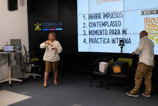 Una mujer está hablando frente a una pantalla que muestra diferentes conceptos relacionados con el desarrollo personal.